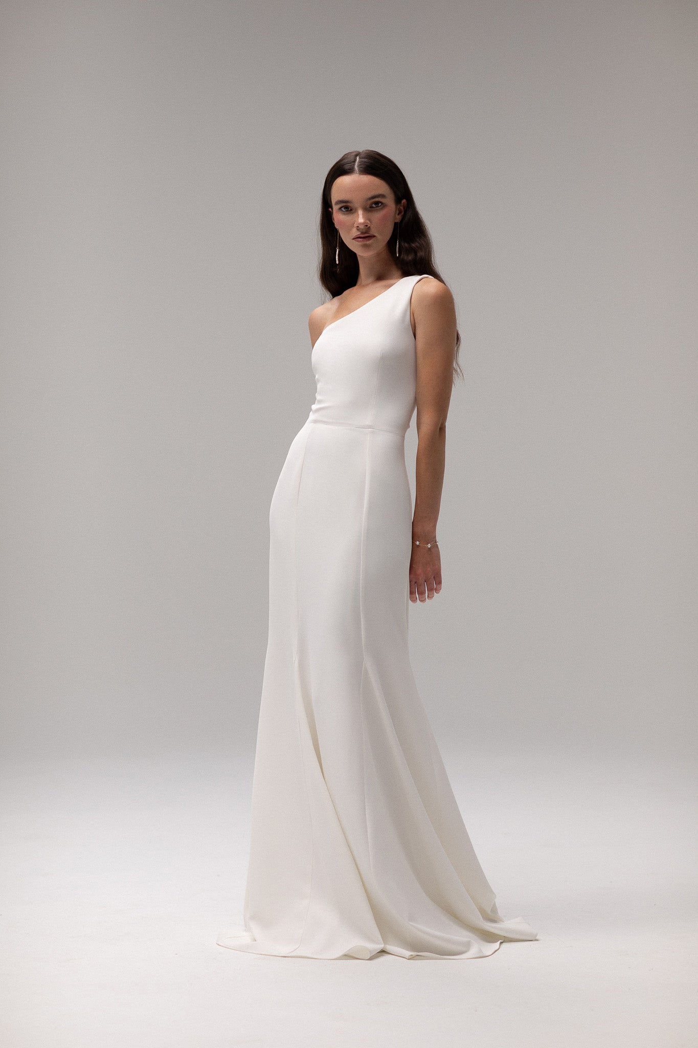 Close-up of crepe one shoulder gown from TEMPÊTE, highlighting its elegant crepe fabric and unique one-shoulder design.