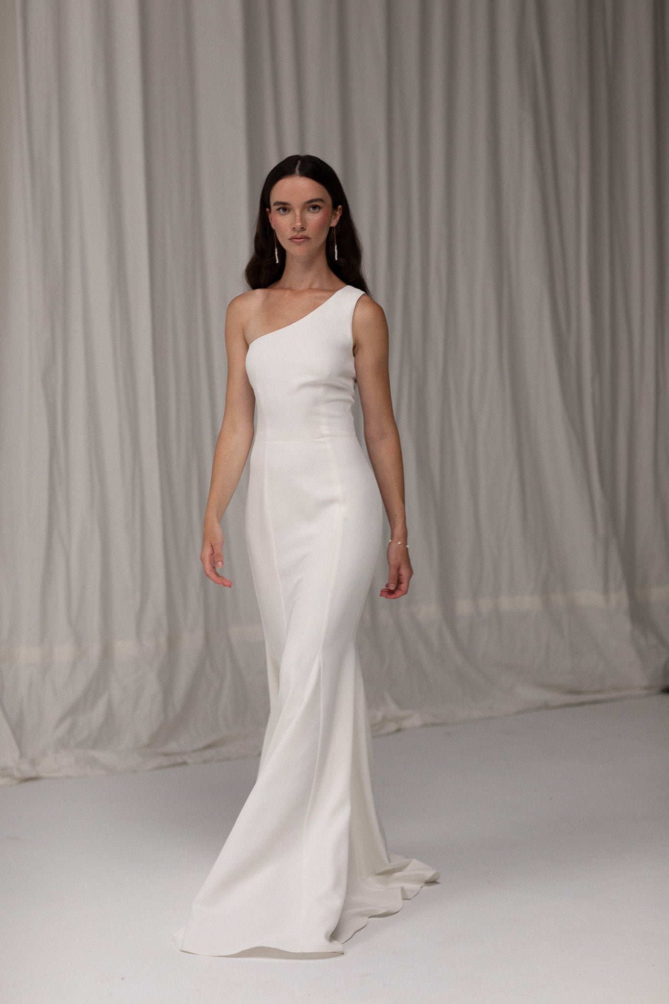 Close-up of crepe one shoulder gown from TEMPÊTE, highlighting its elegant crepe fabric and unique one-shoulder design.