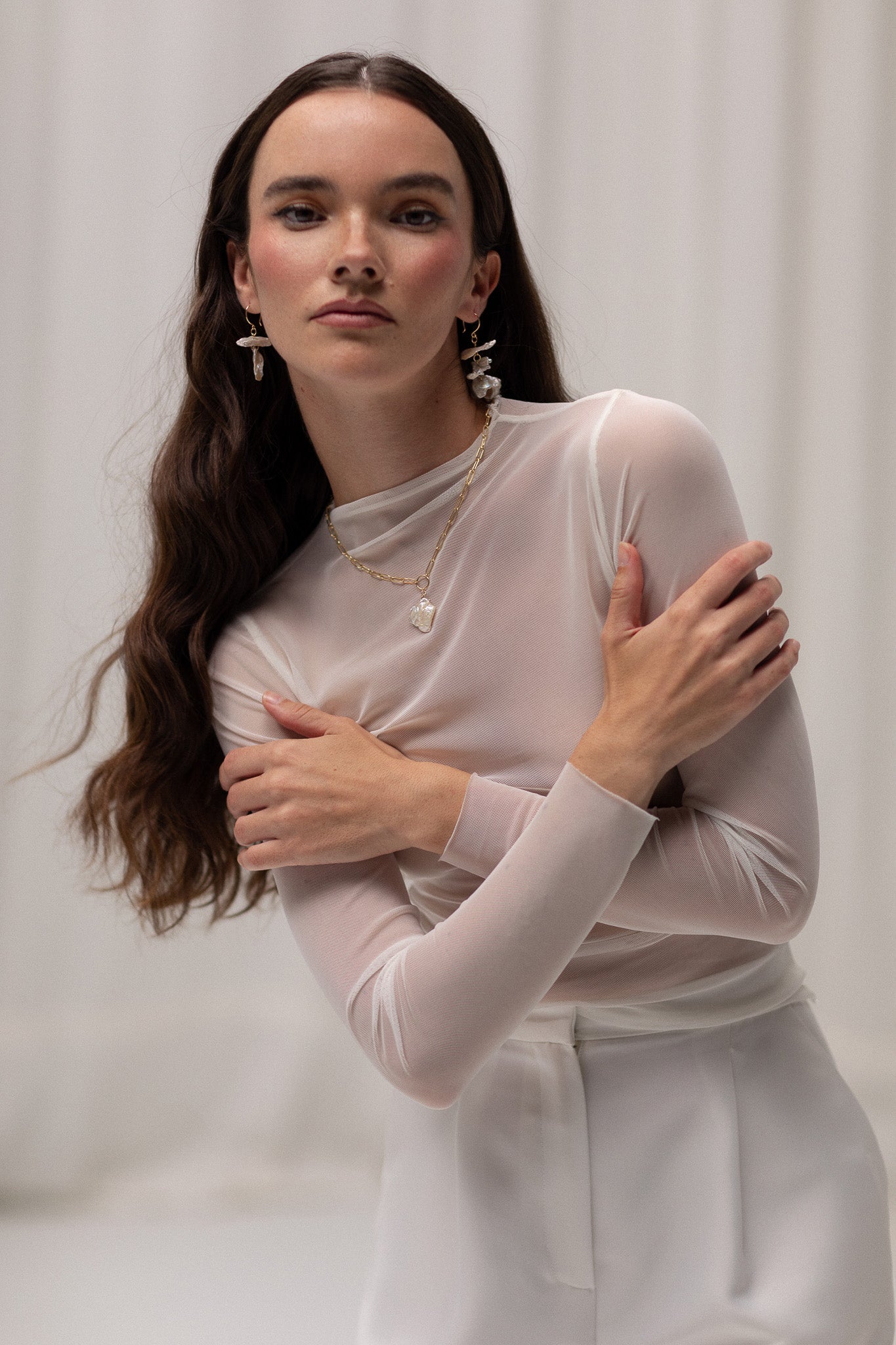 Model wearing a long sleeve mesh top by TEMPÊTE, featuring a sheer design perfect for layering over or under bridal outfits