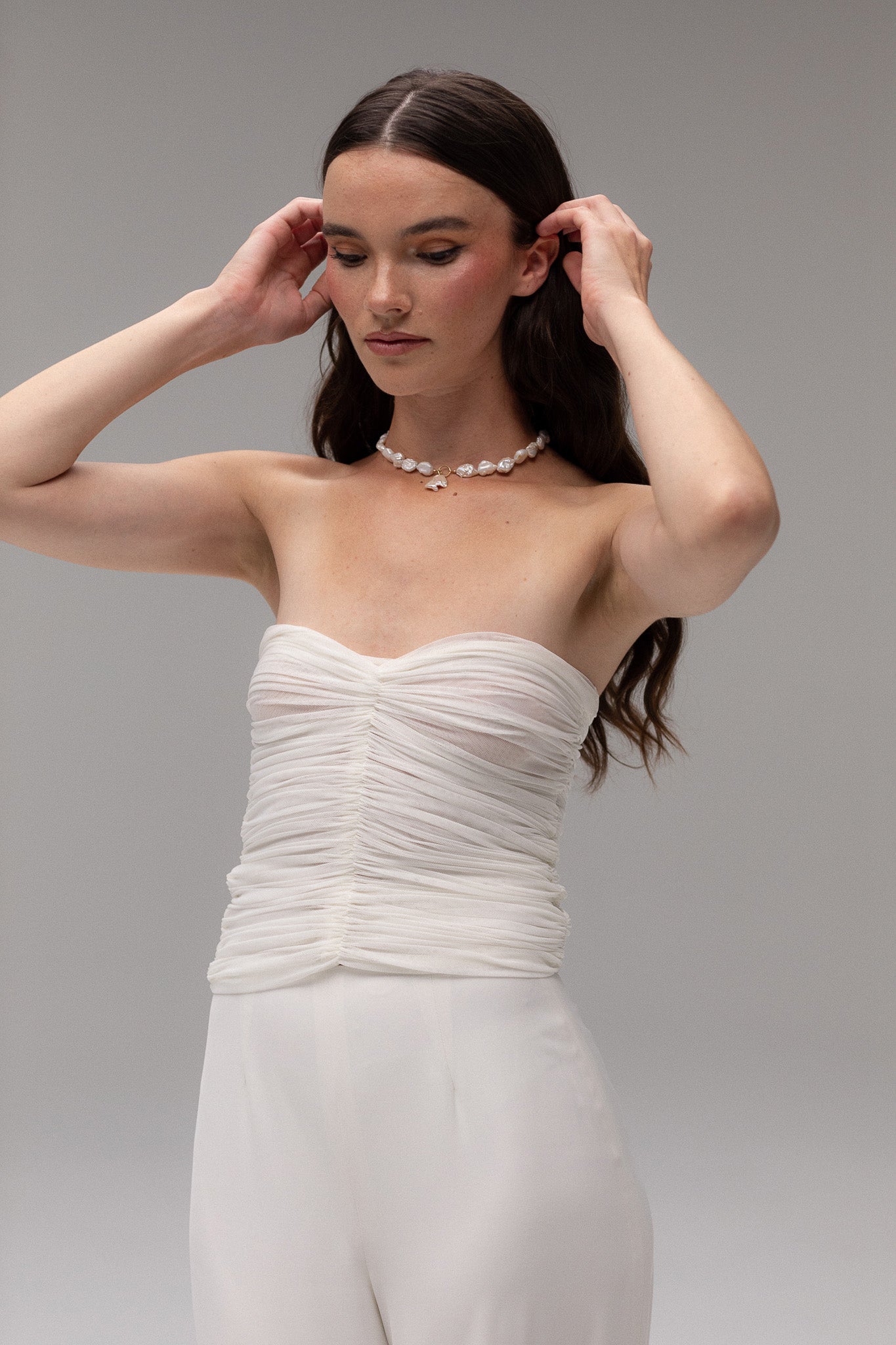 Model wearing a ruched mesh bandeau top from the J'OSE Collection by TEMPÊTE, featuring a modern, strapless design perfect for a chic bridal look