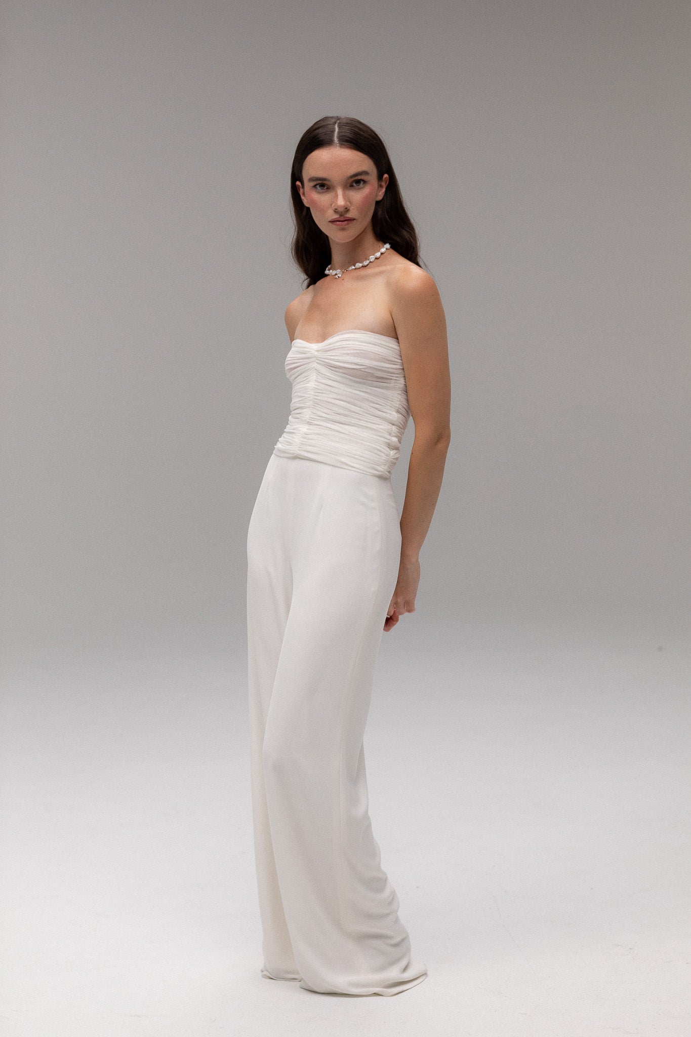 Model wearing a ruched mesh bandeau top from the J'OSE Collection by TEMPÊTE, featuring a modern, strapless design perfect for a chic bridal look