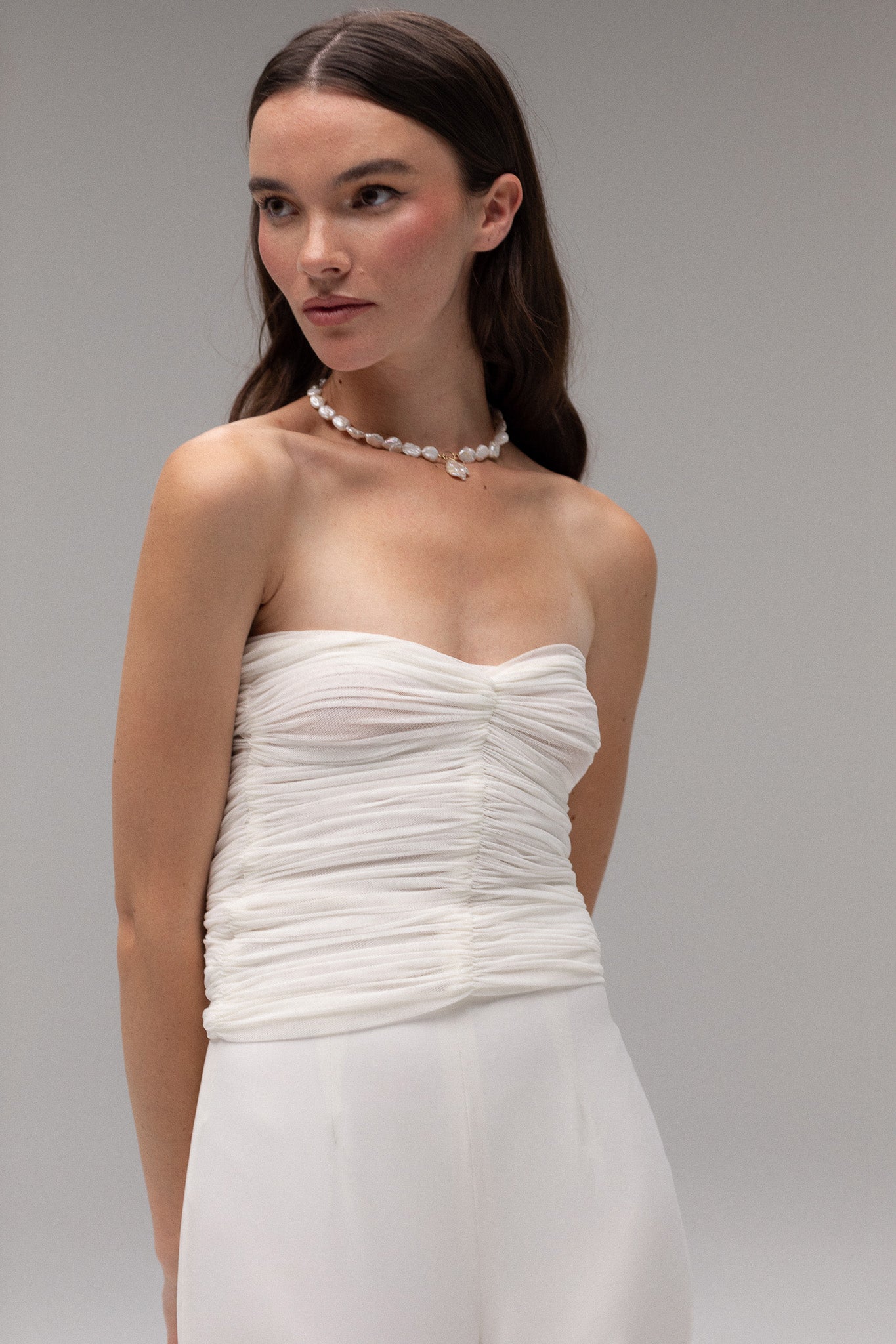 Model wearing a ruched mesh bandeau top from the J'OSE Collection by TEMPÊTE, featuring a modern, strapless design perfect for a chic bridal look