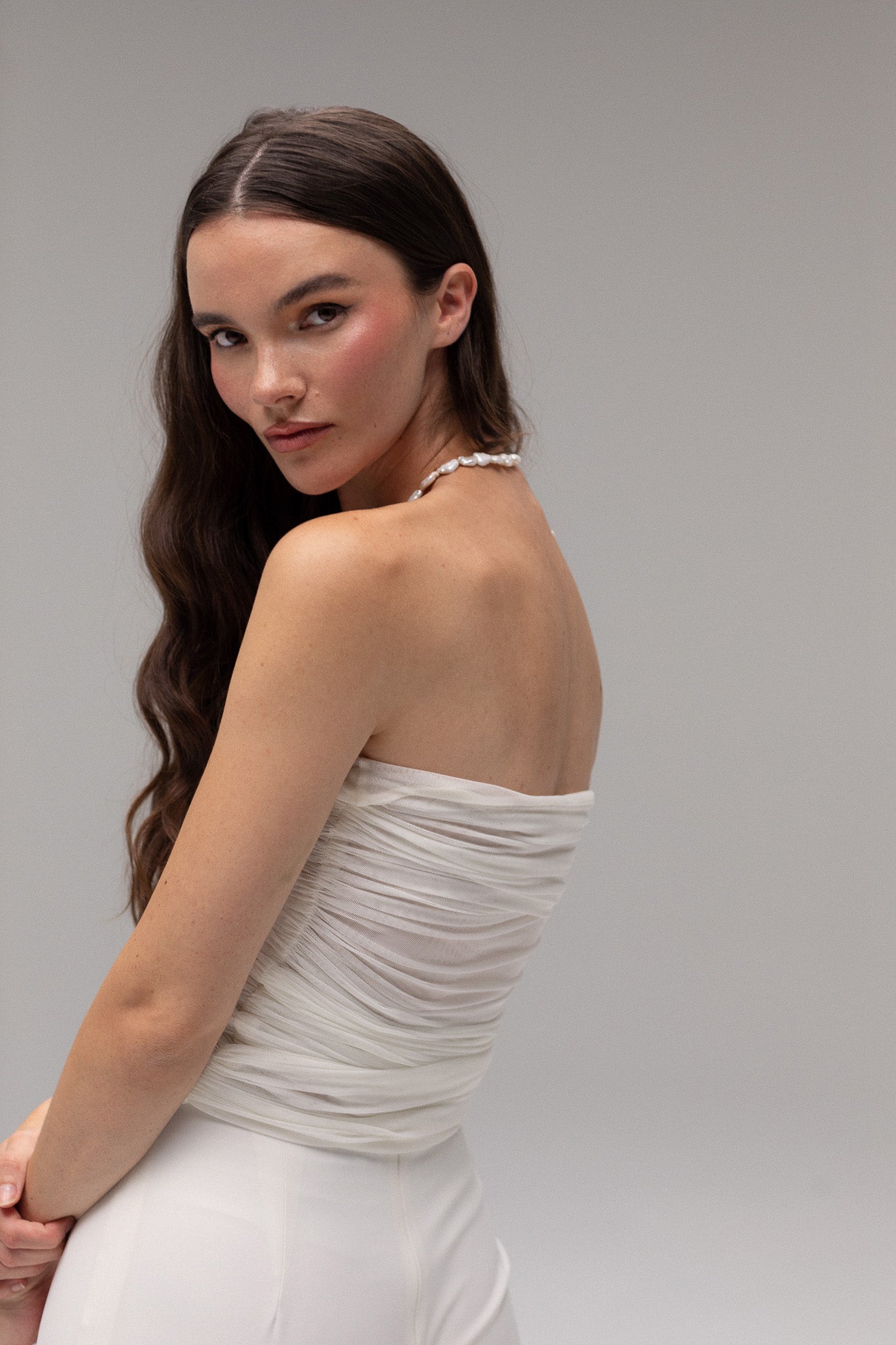 Model wearing a ruched mesh bandeau top from the J'OSE Collection by TEMPÊTE, featuring a modern, strapless design perfect for a chic bridal look