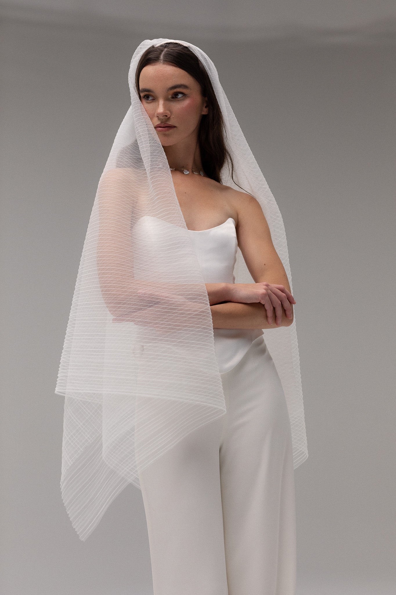 Bride in TEMPÊTE’s blusher pleated tulle veil, showcasing a unique pleated design that adds texture and dimension to a wedding look.