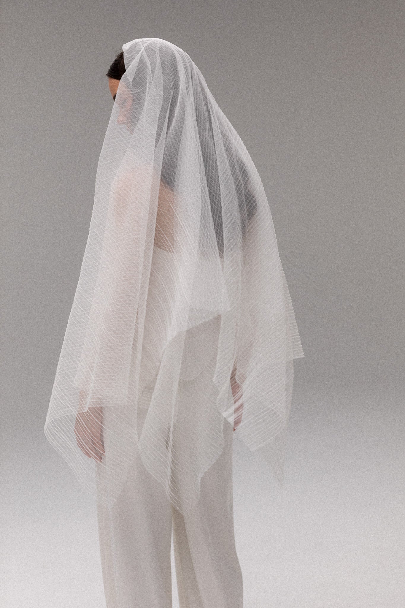 Bride in TEMPÊTE’s blusher pleated tulle veil, showcasing a unique pleated design that adds texture and dimension to a wedding look.