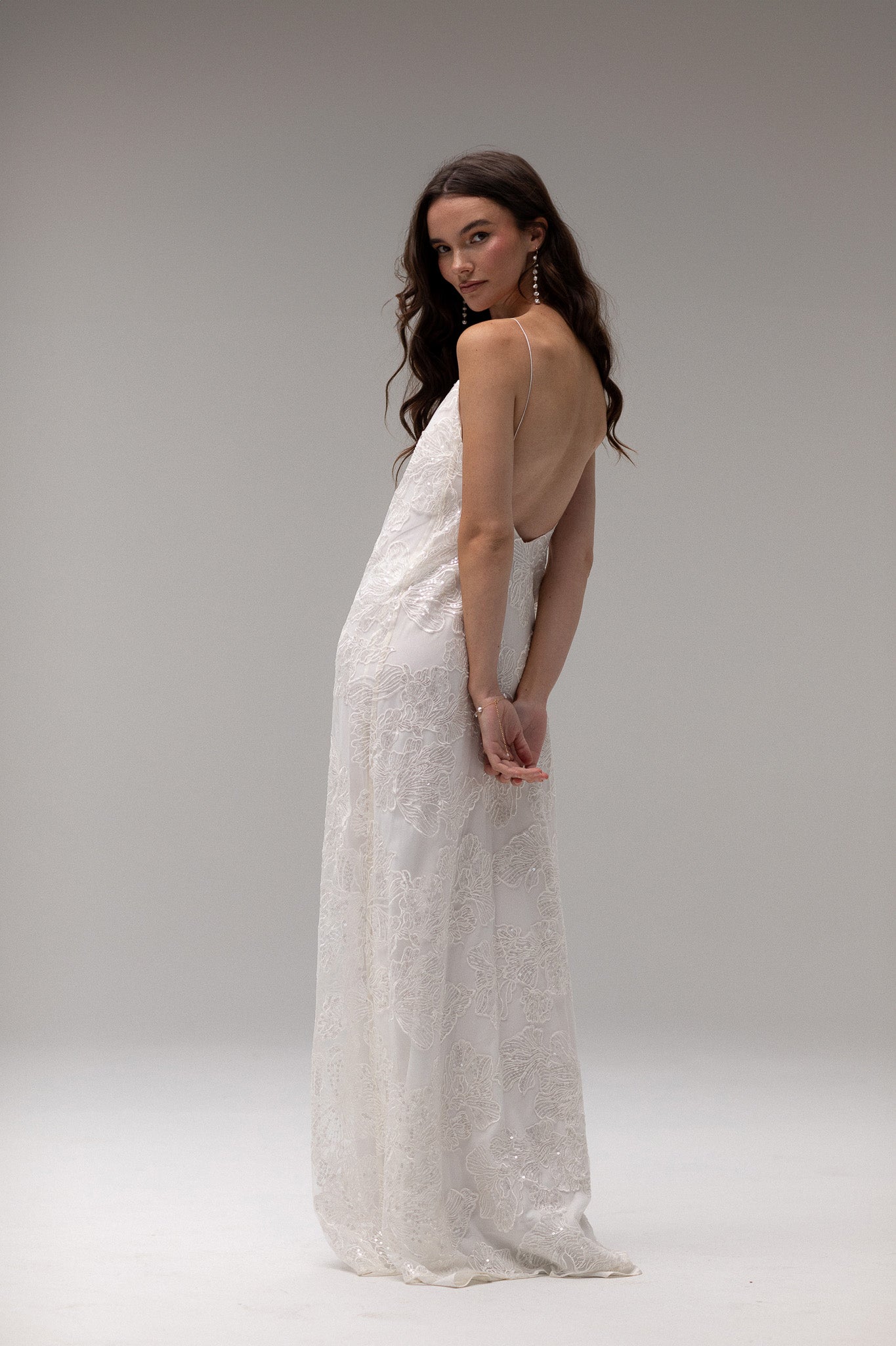 Detailed view of TEMPÊTE maxi bridal dress with delicate sequin lace, v-neck design, spaghetti straps, and an open back, ideal for a modern bridal look