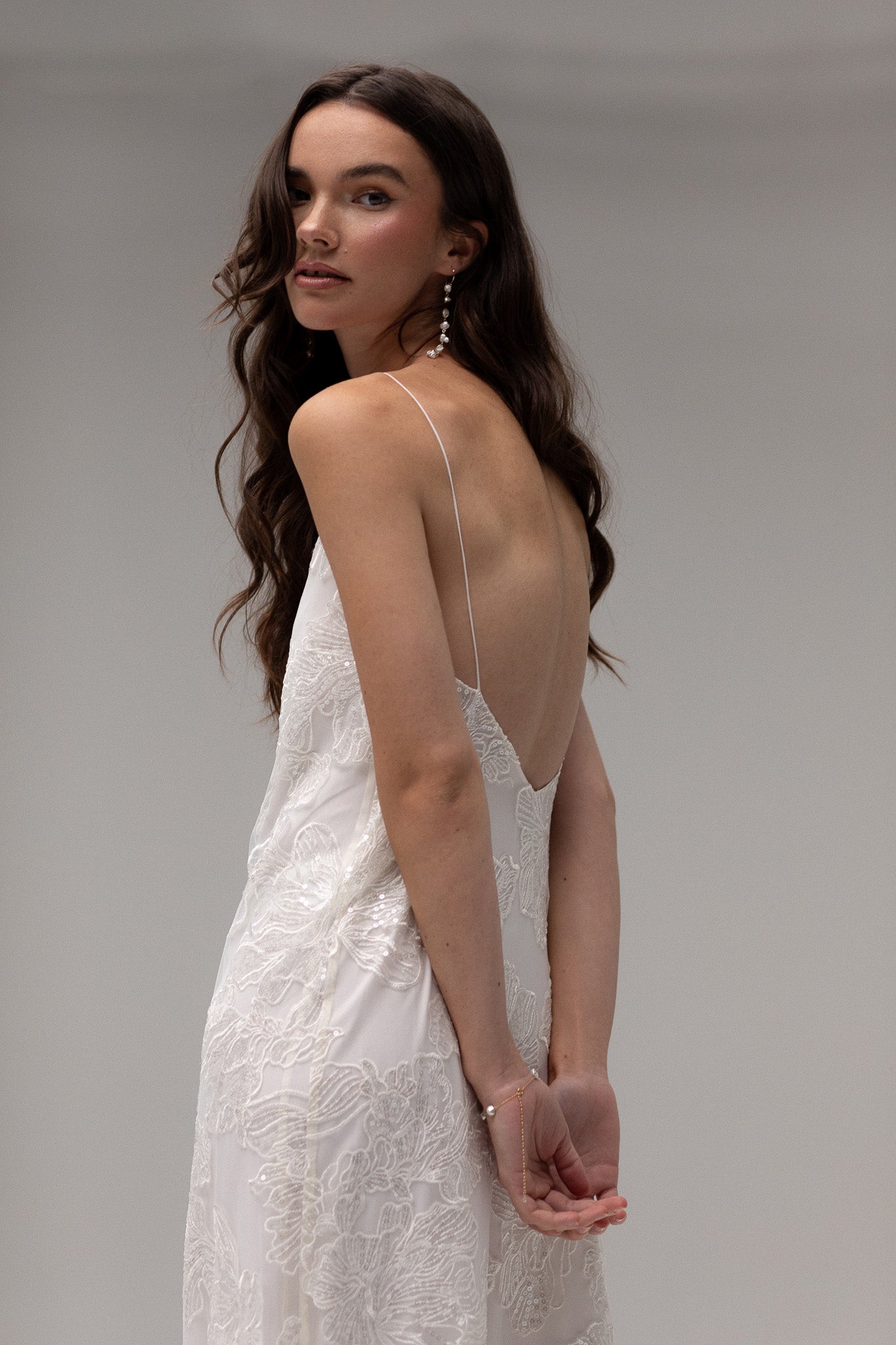 Detailed view of TEMPÊTE maxi bridal dress with delicate sequin lace, v-neck design, spaghetti straps, and an open back, ideal for a modern bridal look