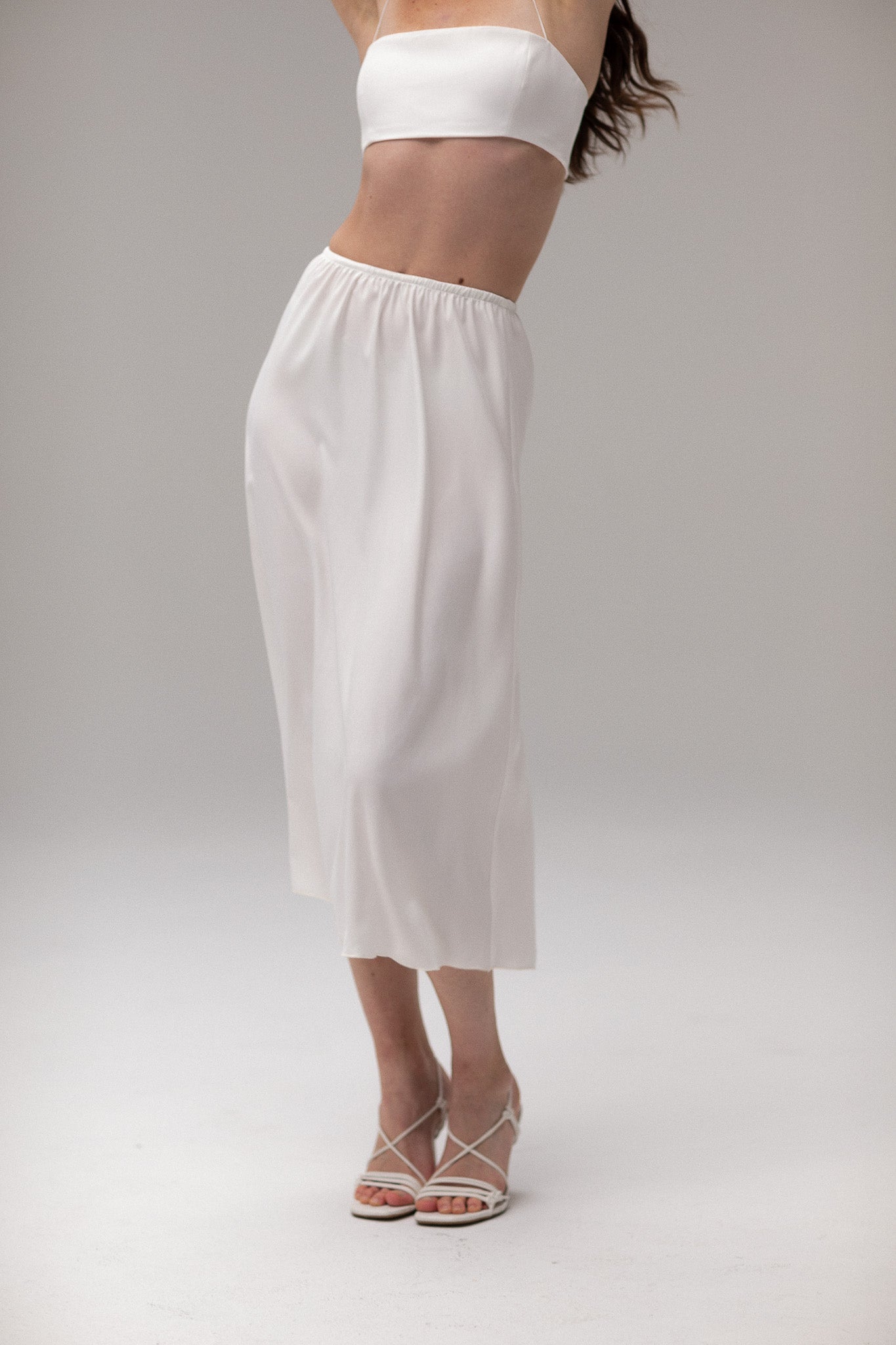 Model wearing a midi satin slip skirt by TEMPÊTE, featuring a smooth satin finish and elegant mid-length.