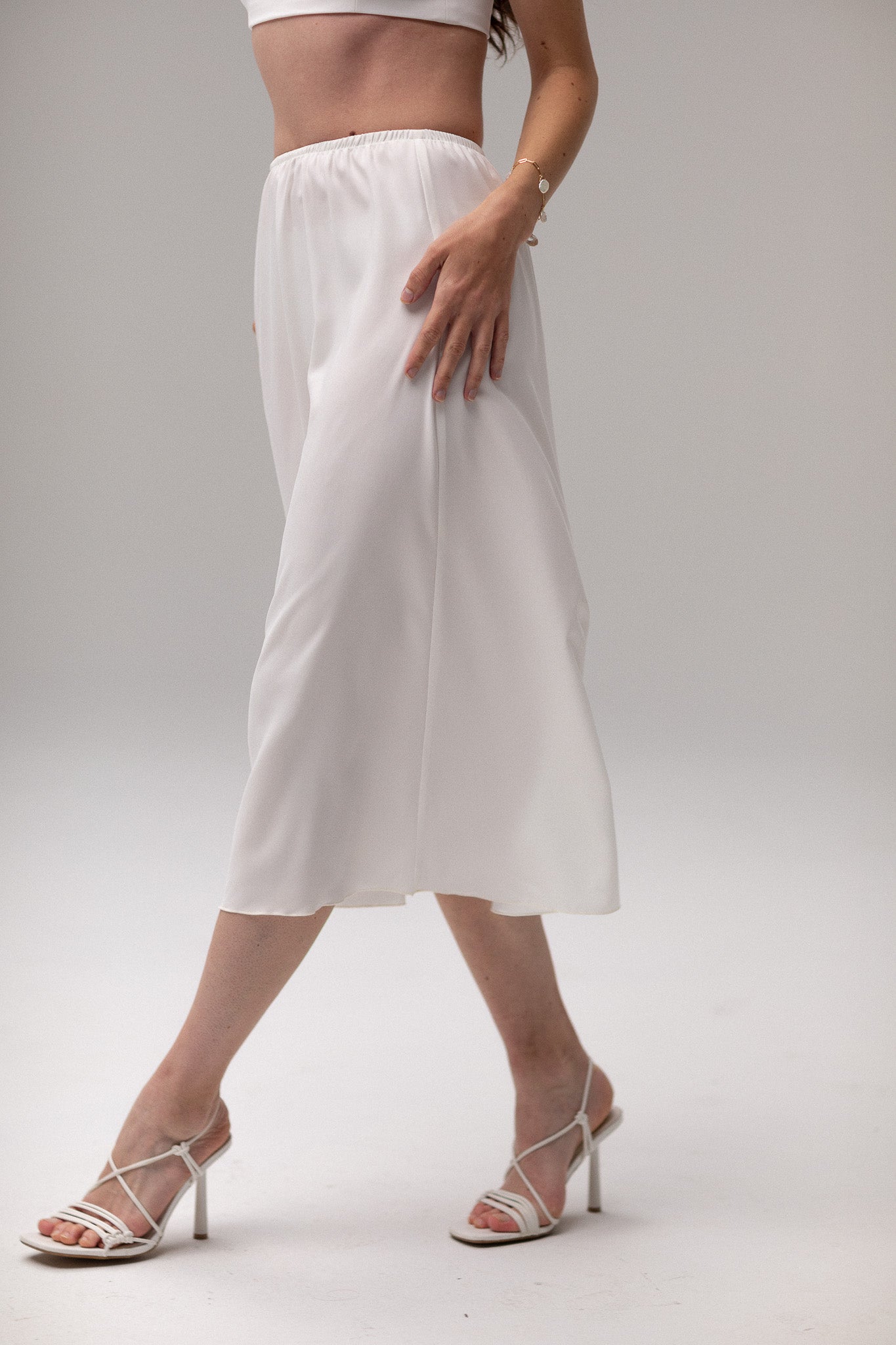 Model wearing a midi satin slip skirt by TEMPÊTE, featuring a smooth satin finish and elegant mid-length.