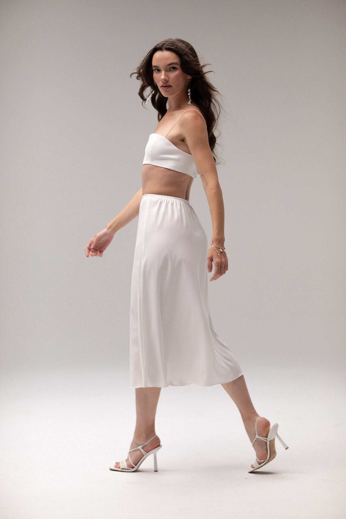 Model wearing a midi satin slip skirt by TEMPÊTE, featuring a smooth satin finish and elegant mid-length.