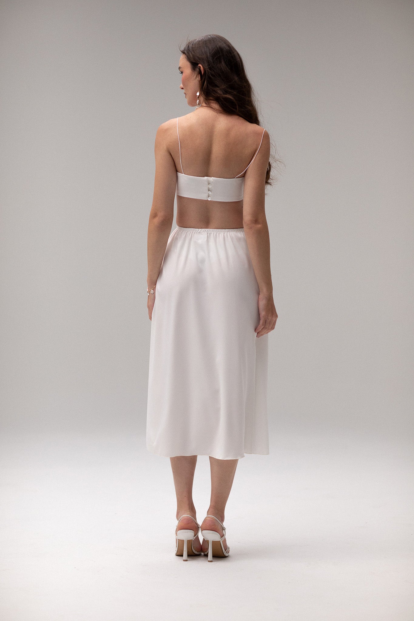 Model wearing a midi satin slip skirt by TEMPÊTE, featuring a smooth satin finish and elegant mid-length.