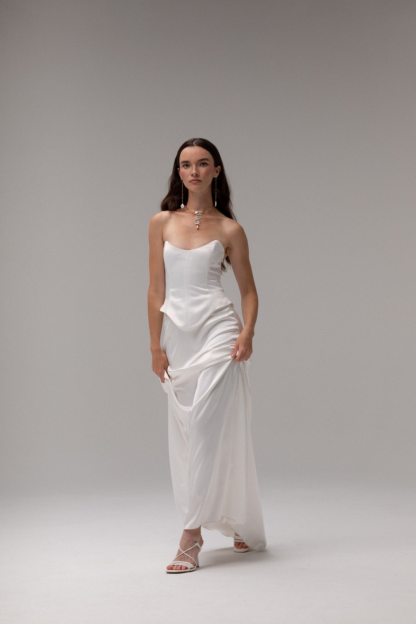 Model wearing a matte satin maxi skirt from the J'OSE Collection by TEMPÊTE, featuring a high-waisted design with a flowing silhouette, perfect for a refined bridal look.