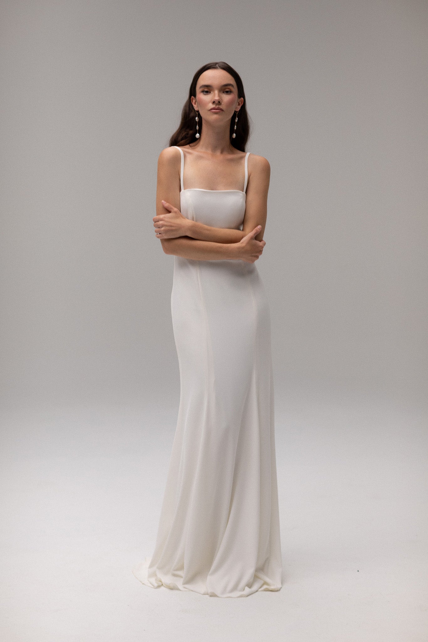 Model wearing an open back crepe gown from TEMPÊTE, featuring a voluminous skirt and square neckline for a sophisticated bridal look.