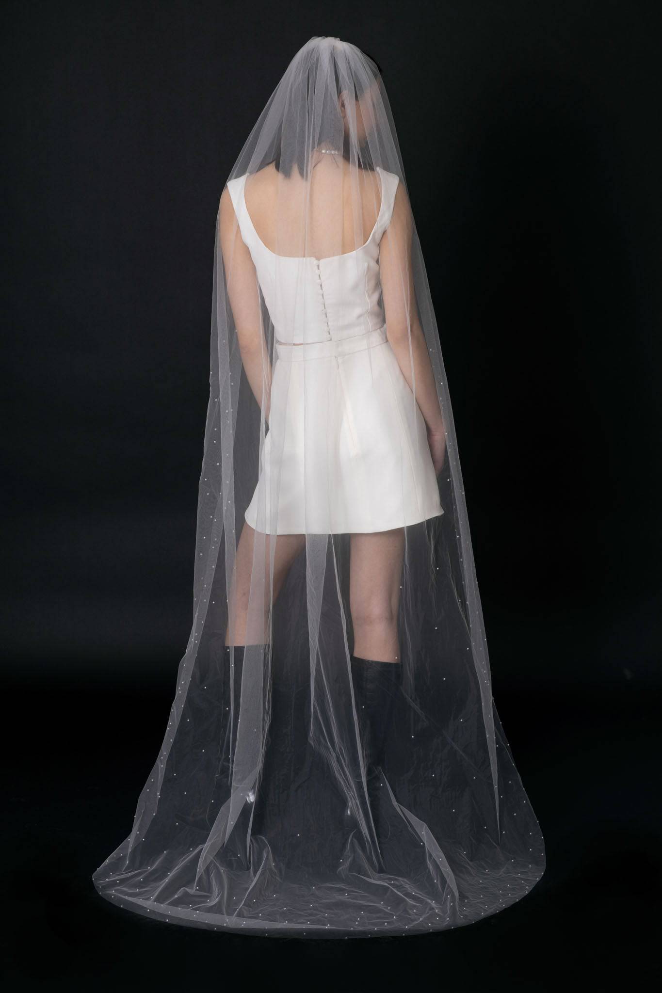 Back of Acacia Pearl Veil by TEMPÊTE, crafted from soft, silky tulle with a delicate pearl trim along the edges, secured with a comb for easy placement.