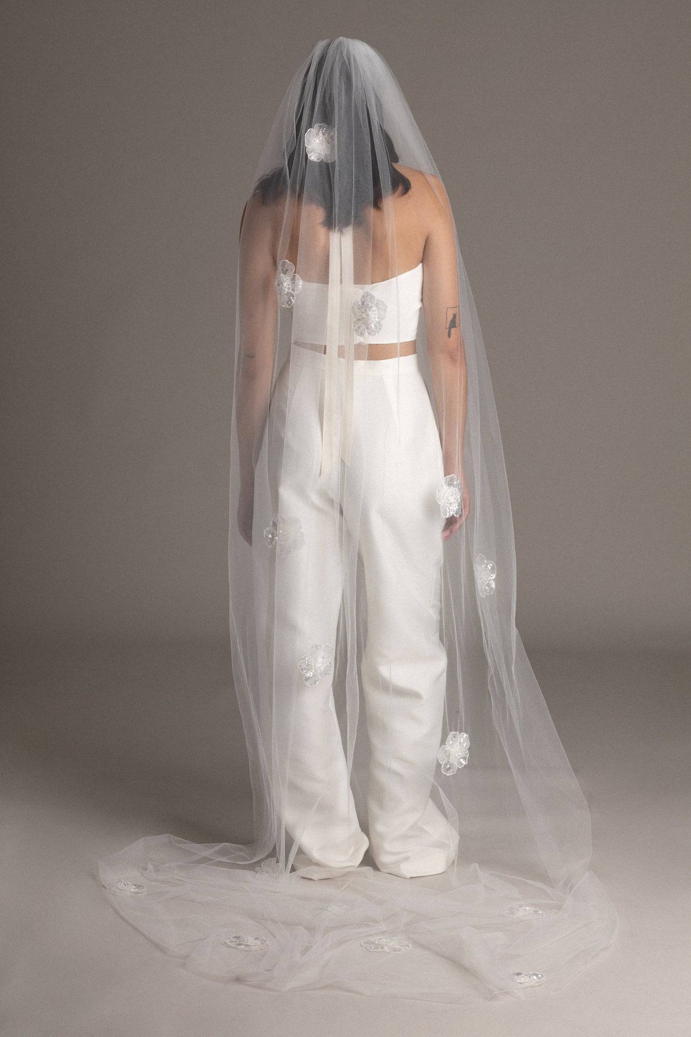 Back view of a bride wearing the Sequin Flower Tulle Veil by TEMPÊTE, featuring delicate sequin flowers that span the length of the veil