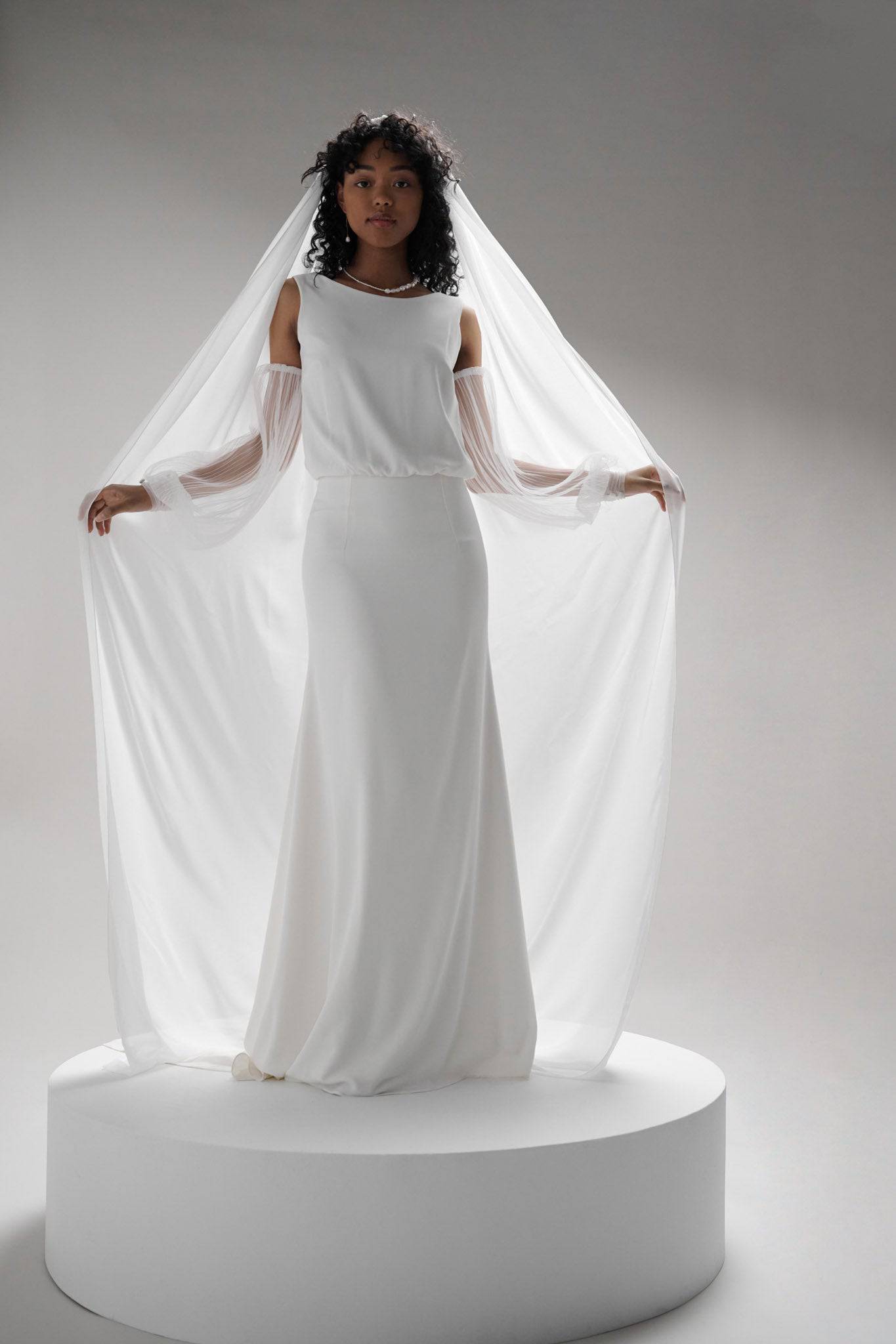 The Soleste Chiffon Veil by TEMPÊTE features a full-length chiffon train, finished with a sleek metal comb, offering a timeless and statement-making bridal look.