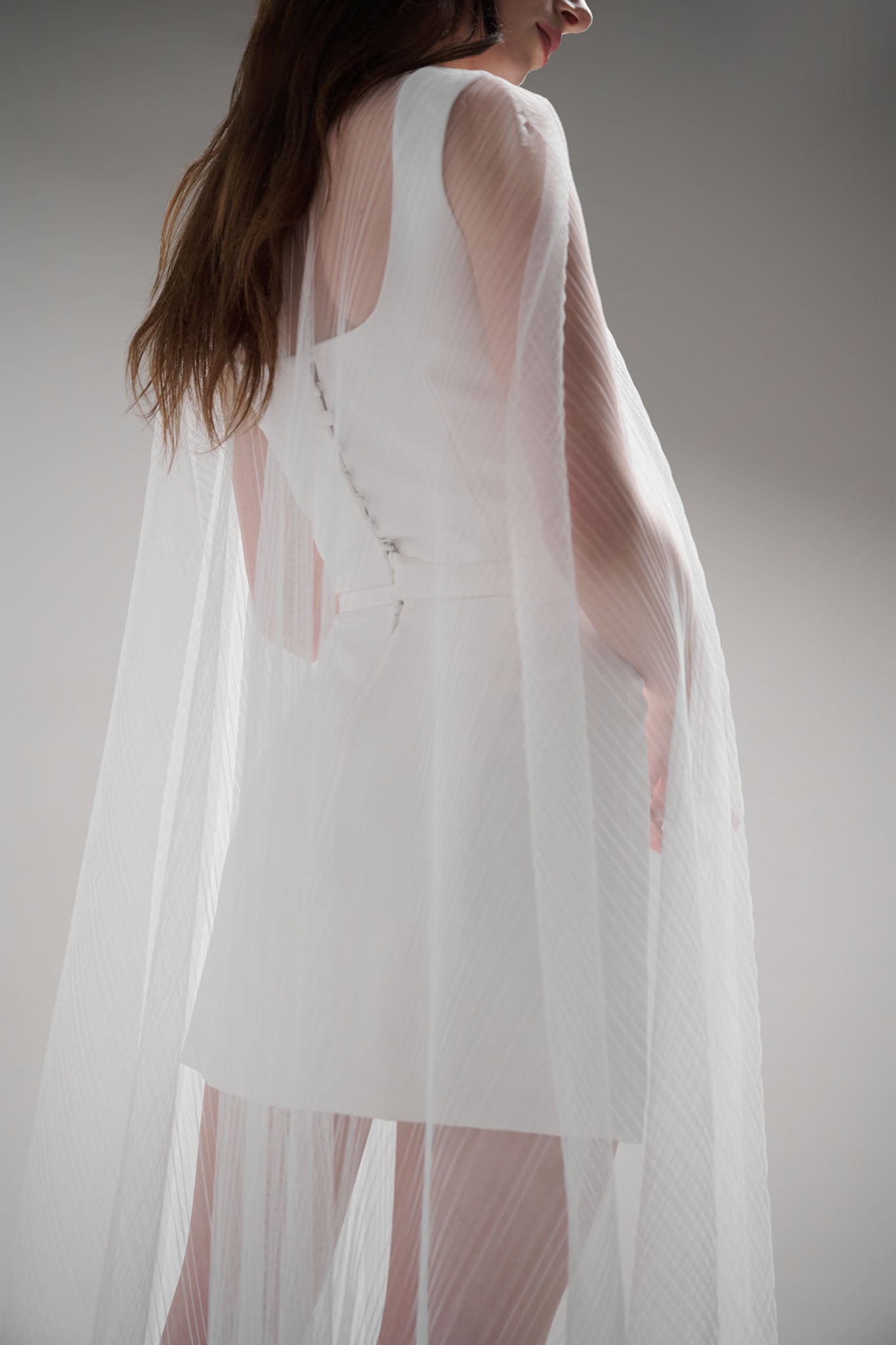 Coquille Cape - a modern veil alternative made with translucent tulle that adds ethereal beauty to any look. Featuring a hidden hook and eye closure for easy removal and showcasing the details underneath, this accessory is an effortless two-in-one outfit